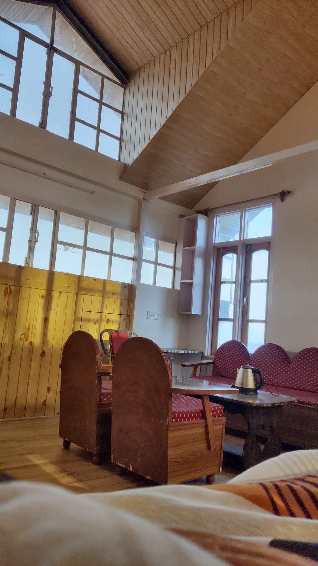 Room at Pinewood with tall windows, wooden walls and a table with chairs