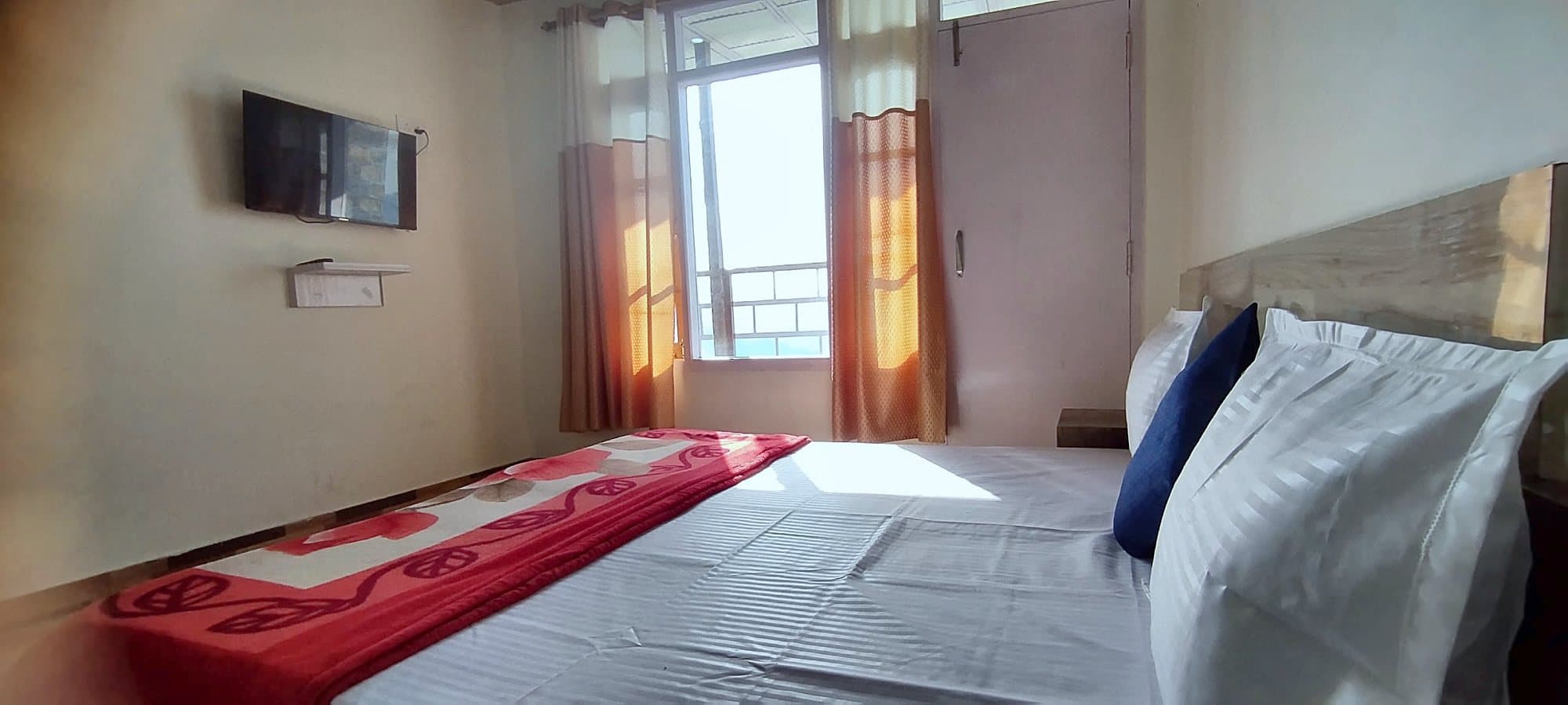 Bedroom at Pinewood with a wall-mounted TV and windows