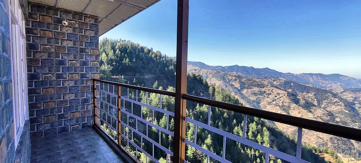 Stone-clad balcony at Pinewood looking out over forested hills under a blue sky