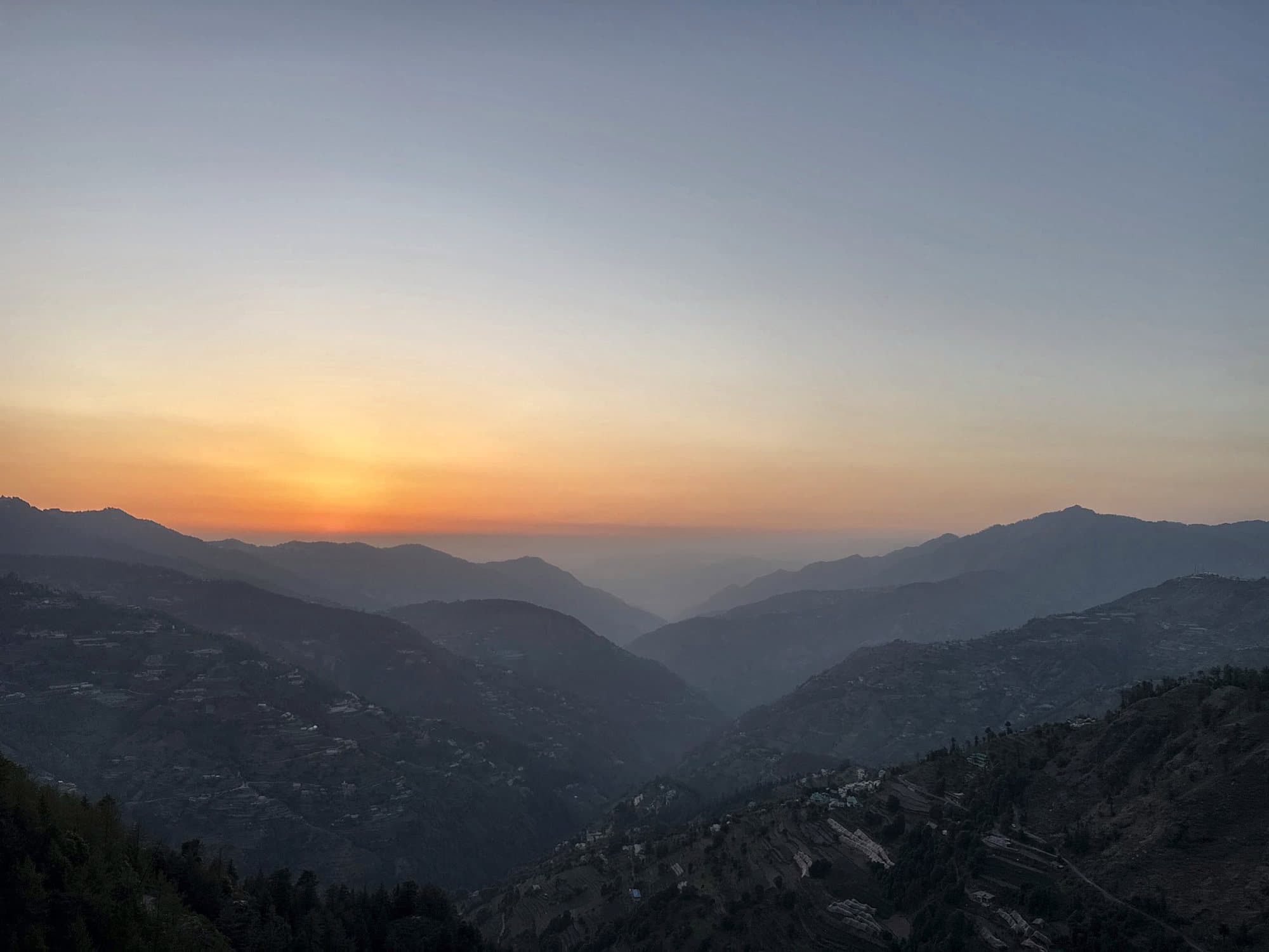 Orange sunset over layered mountain ridges near Kufri