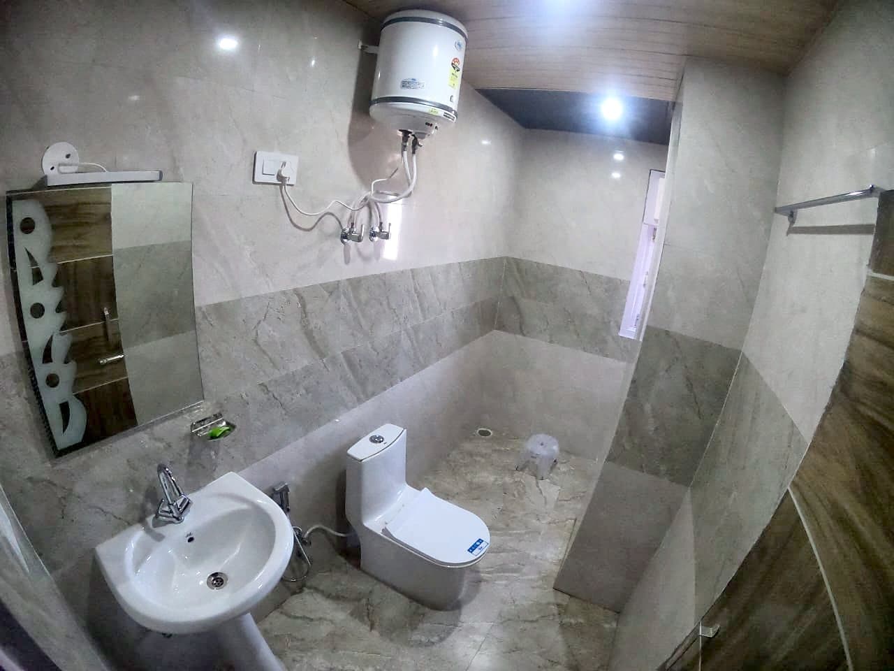 Tiled attached washroom at Pinewood with a geyser, washbasin and toilet